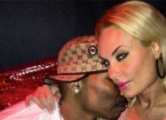Coco Austin smirking at the camera and wrapping her arm around AP.9 as he plants a kiss on her cheek and burrows his face in her neck