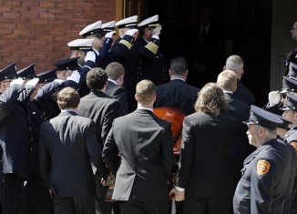 Firefighters honor guard salute as pallbearers carry the casket of Boston Marathon bomb victim Krystle Campbell into St Joseph's Church for her funeral in Medford