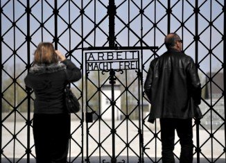 Angela Merkel has laid a wreath at the former Nazi concentration camp of Dachau, in the first such visit to the site by a German chancellor